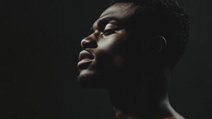 Close-up profile view of a man, serene expression, dark background. Potential use Stock photo for self-care, mindfulness, or introspection
