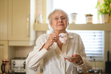 portrait of senior woman standing at home hold coffee