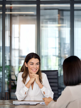 Happy mature professional business woman executive hr manager having job interview or business discussion with female applicant or colleague sitting at workplace in corporate office meeting.
