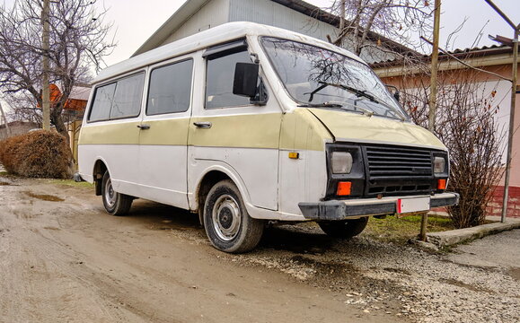 An old Soviet minibus  parked on the roadside in a residential area. Visible signs of rust and wear. - Powered by Adobe