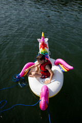 Dzieci pływają na dmuchanym jednorożcu, bawią się i pluskają w wodzie, słońce pięknie świeci © Katarzyna Krociel