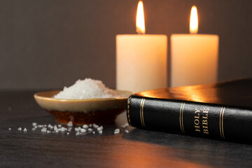 Holy bible book, salt, and candles burning in the background. Close-up. Copy space. Christian...