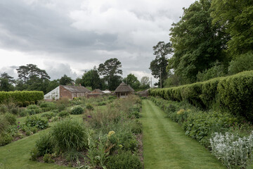 pretty borders in an English garden leading down to a thatched gazebo