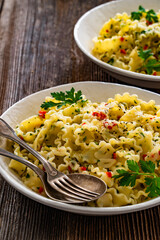 Pasta with garlic, parsley and pepperoncino on wooden table. Boiled mafaldine noodles. Spaghetti aglio olio e peperoncino on wooden background