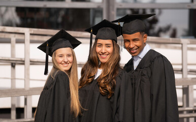 Happy multiethnic graduates smiling and celebrating graduation day looking at camera