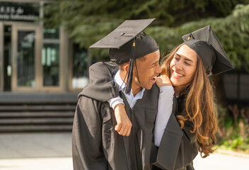 Two happy multiethnic students celebrating graduation day at university campus