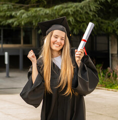 Happy graduate celebrating with diploma, graduation gown and mortarboard