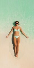 Fototapeta premium A woman is laying on the beach in a bikini. She is wearing sunglasses and she is relaxed