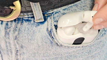 fingers delicately holding a smart earbud against a neutral background.