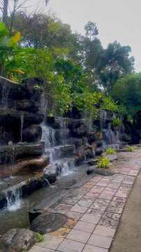 A human-made fountain in a park, with water flowing gracefully, adding beauty and tranquility to the surroundings.