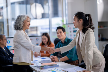 A woman shakes hands with another woman in a business setting