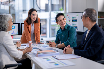 A group of people are sitting around a table with papers and graphs
