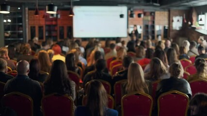 Attendees seated in a hall listen attentively to a presentation during an event focusing on learning.