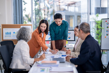 A group of people are sitting around a table with a whiteboard behind them