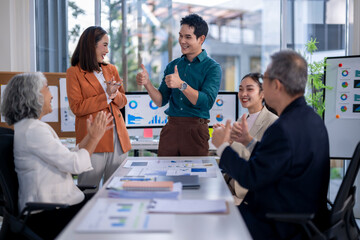 A group of people are clapping and smiling at each other in a conference room