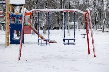 Children's swings in the park on the playground in winter