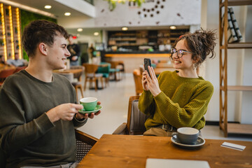 girlfriend use mobile phone to take a photo of her boyfriend at cafe