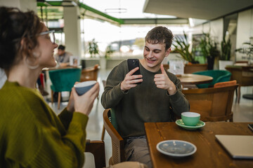 boyfriend use mobile phone to take a photo of his girlfriend at cafe