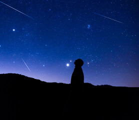 Fototapeta premium Silhouette of a man observing Milky Way stars from a dark countryside location..
