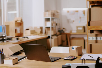 Neatly arranged office supplies and cardboard boxes in modern office setting with laptop, calculator, and paperwork on desk promoting efficient arrangement and productivity