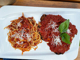 A Parmesanschnitzel, Parmesan escalope, escalopina Parmigiani, on a white plate in an Italian restaurant