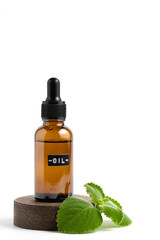 Bottle of mint essential oil on wooden stand with fresh mint leaves highlighted on white background.