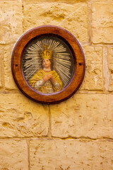 Religious Portrait Framed in Wood Hanging on Textured Stone Wall