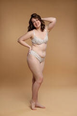 Fototapeta premium Beautiful woman in underwear on dark beige background. Cellulite problem