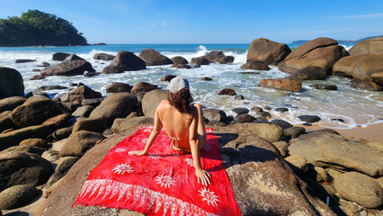 Mujer tomando el sol en una playa con rocas en Brasil