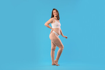 Fototapeta premium Woman in underwear on light blue background. Cellulite problem