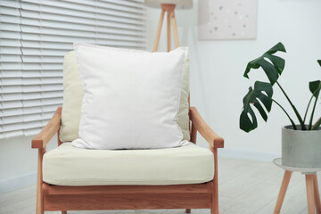 Blank soft pillow on cozy armchair at home