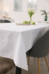 Table with white tablecloth and chair indoors, closeup