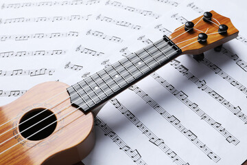 One ukulele on music sheets, closeup view