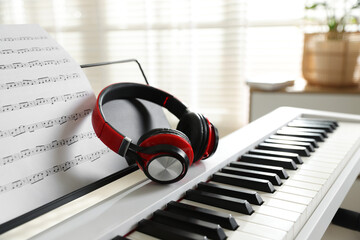 Synthesizer with music sheet and headphones indoors, closeup