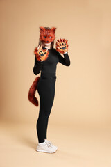 Quadrobics. Girl wearing fox mask, gloves and tail on beige background