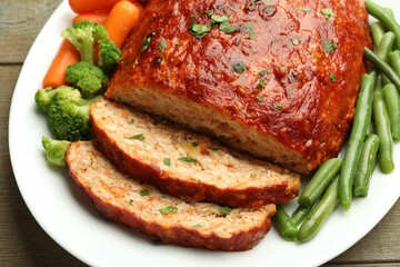 Delicious baked turkey meatloaf with vegetables on wooden table, closeup