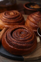 Delicious cinnamon roll buns on wooden table, closeup