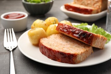 Delicious baked turkey meatloaf with potatoes served on grey table, closeup