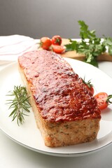Delicious baked turkey meatloaf, rosemary, cherry tomatoes and parsley on white table, closeup