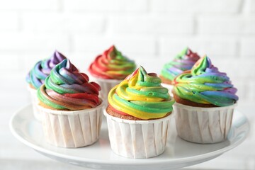 Delicious cupcakes with colorful cream on stand against blurred background, closeup