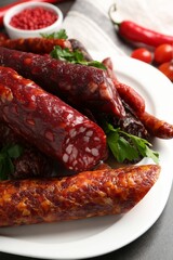 Different smoked sausages and parsley on grey table, closeup