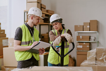 Colleagues examining shipment details during warehouse operations employee holding documents and discussing logistics for inventory management