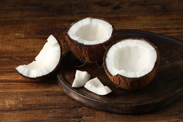 Pieces of cracked coconuts on wooden table, closeup