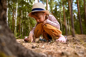 A little tourist girl exploring nature, soil and insects