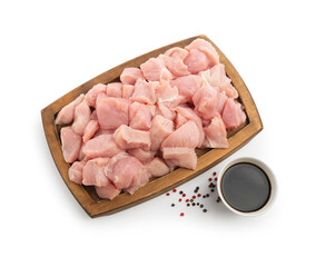 Wooden board with pieces of raw turkey meat, soy sauce and peppercorns isolated on white, top view