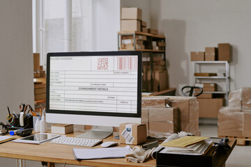 Employee working with computer and packaging materials in warehouse, preparing shipments and...
