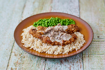 chicken fried steak on a bed of rice served with peas