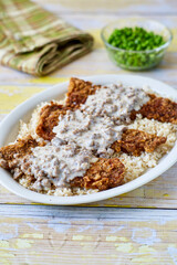 chicken fried steak topped with sausage gravy on a bed of rice