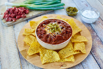 beef chili topped with shredded cheese and jalapeno served with tortilla chips
