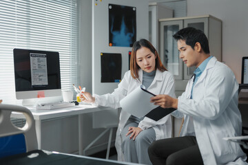 Fototapeta premium Doctors reviewing medical records discussing patient diagnosis in hospital room